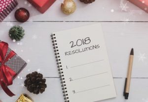2018 resolutions on Note book and pen with Christmas and New Year holidays gift box with decorative ornament on wooden table.Gifts and congratulations concept.
